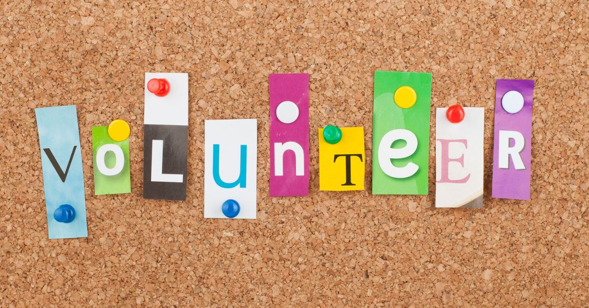 Letters pinned to a corkboard spelling out the word 'volunteer'