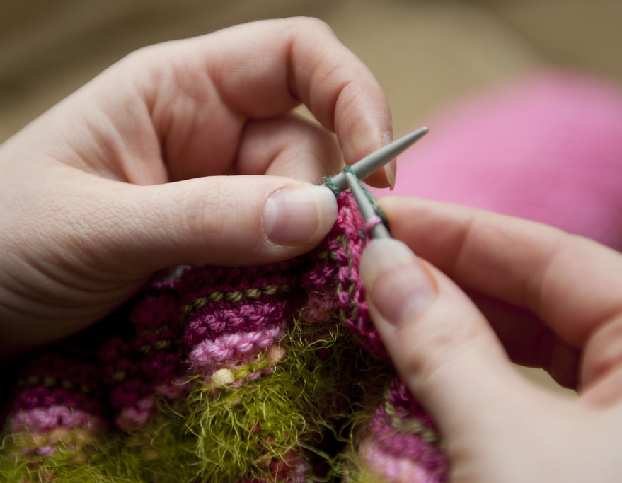 a person knitting yarn with two needles