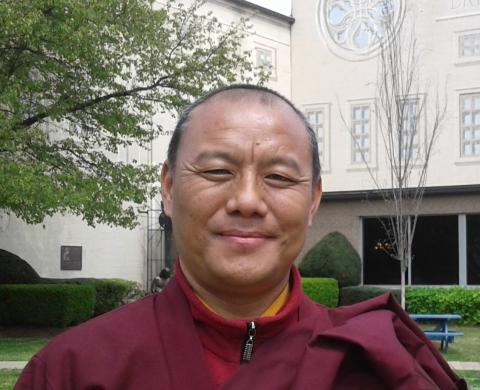 a picture of a monk in red robes in front of a white building