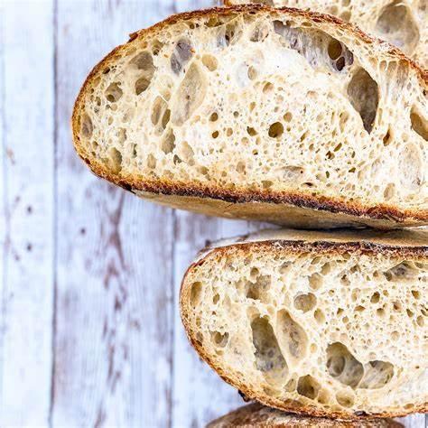 several sliced of sourdough bread on a white wood background