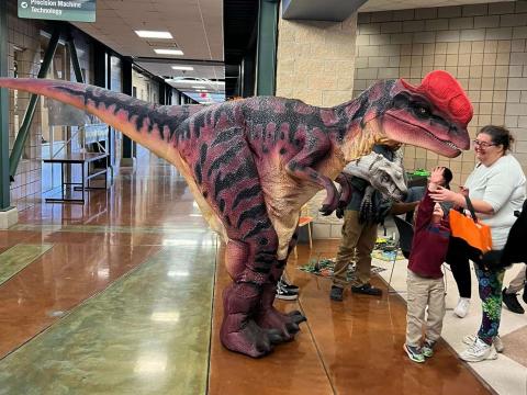 large dinosaur greeting children and parents