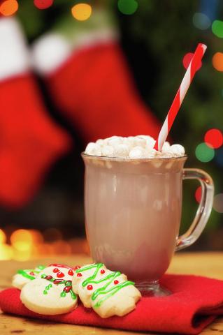 glass mug of hot cocoa with tree shaped cookies on red napkin