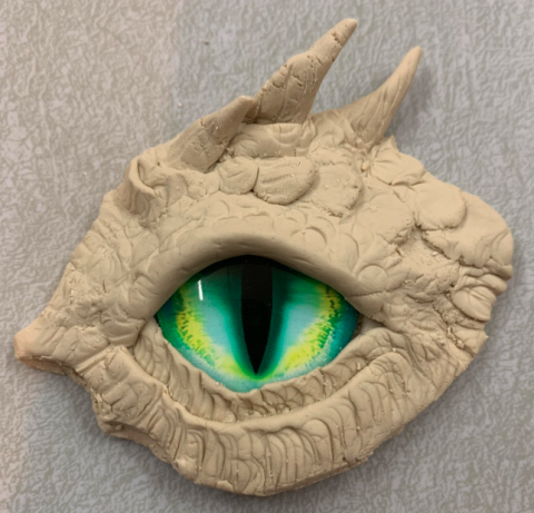 A dragon eye sculpted out of clay and a glass bead