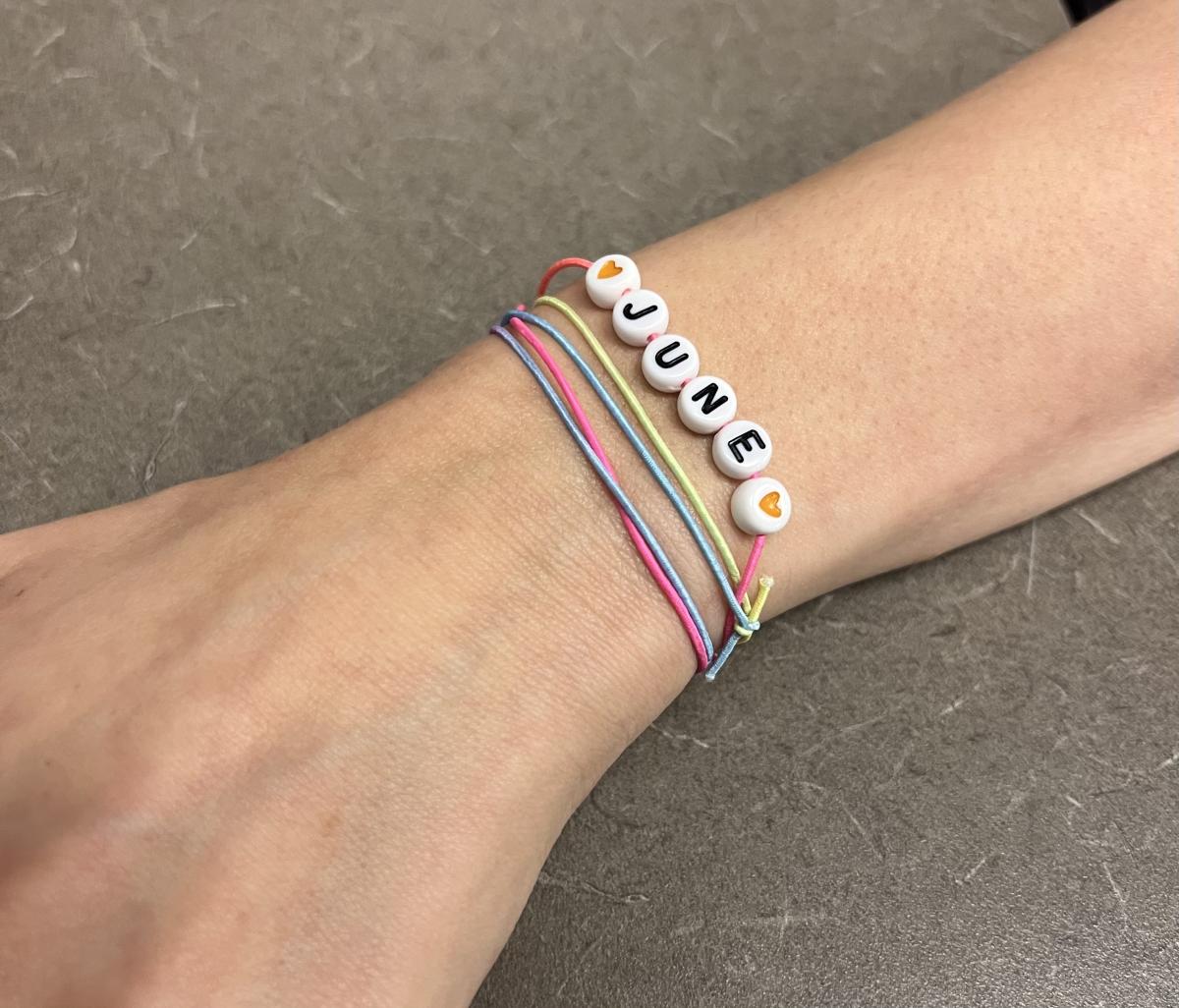 Person wearing rainbow bracelet spelling June