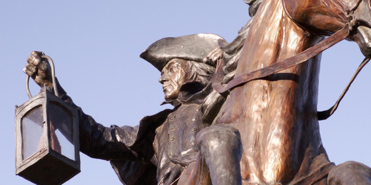 Photo of bronze statue of Paul Revere holding a lantern on a horse.