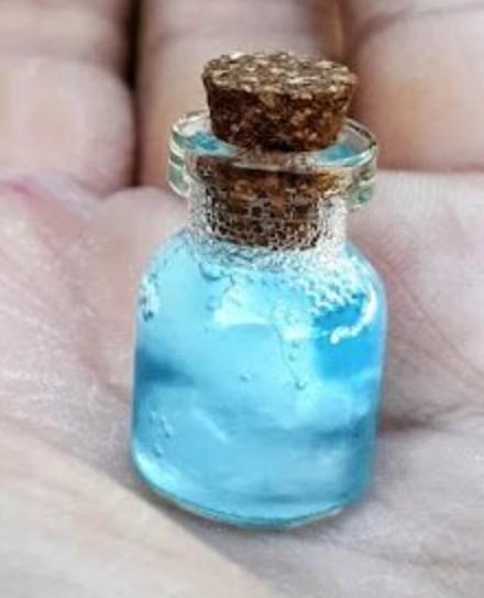 A tiny glass bottle filled with blue liquid