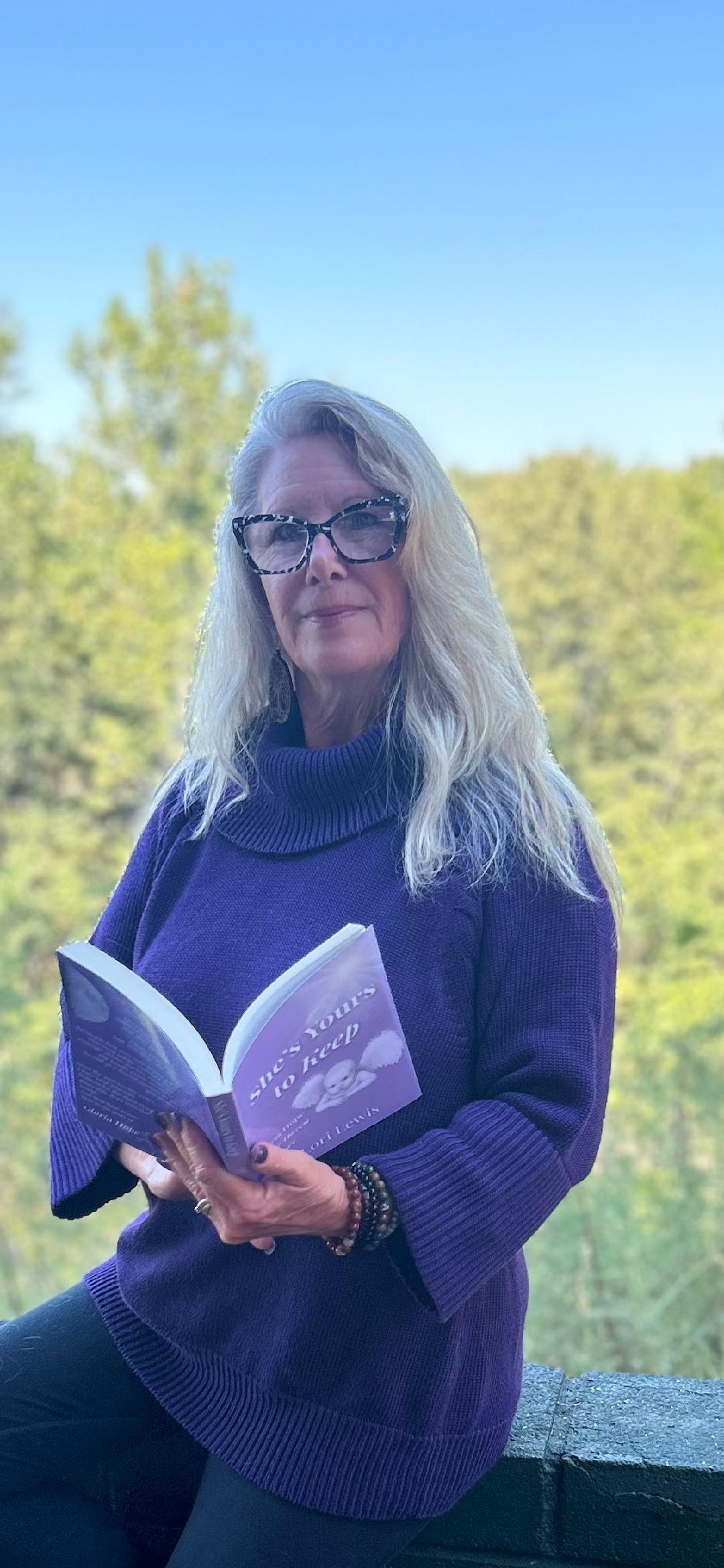woman sitting outside holding a book